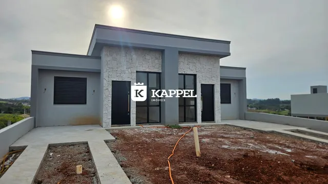 Fachada moderna de uma casa residencial em Lajeado, Brasil, com revestimento de pedra e acabamento em estuque cinza.