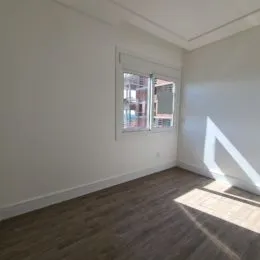 Foto de um cômodo interno com paredes brancas e piso de madeira.
