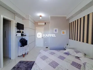 Quarto com cama e televisão em um ambiente claro com piso de cerâmica.
