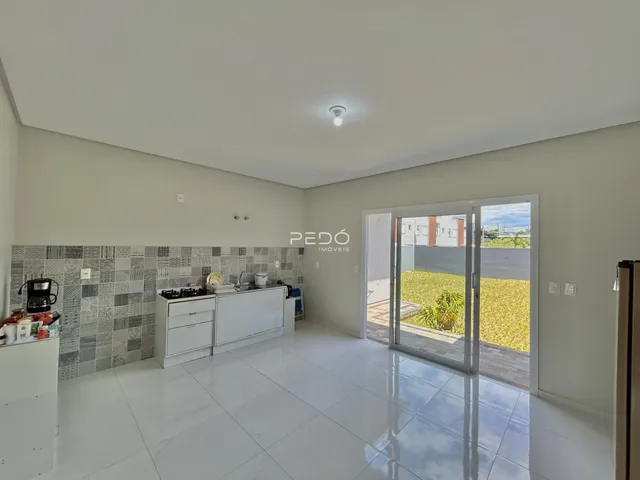 Ambiente de sala e cozinha com piso de cerâmica e porta de vidro.