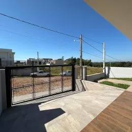 Vista externa de um pátio com grade metálica e paisagem seca ao fundo.
