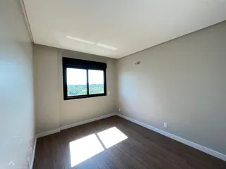 Uma sala de estar com piso de madeira e uma grande janela voltada para a paisagem externa.