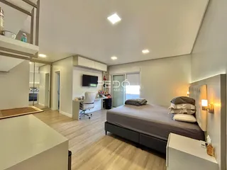Quarto moderno com cama e área de estar em um apartamento.