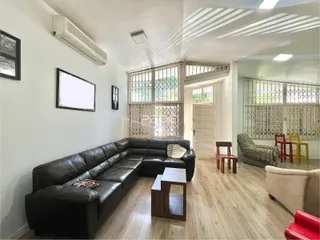 Sala de estar com sofá de couro e piso de madeira clara.