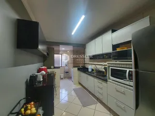 Vista da cozinha de um imóvel em Lajeado, Brasil, com armários brancos e eletrodomésticos de aço inoxidável.