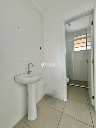Interior de um banheiro com pia de pedestal e piso de cerâmica.