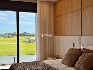 Quarto com vista para a paisagem externa através de uma grande janela.
