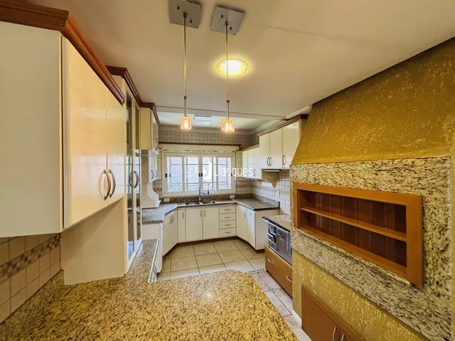 Vista interna de uma cozinha com armários brancos e detalhes em pedra.
