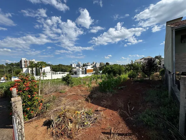 Vista externa mostrando terreno seco com vegetação rasteira e um horizonte urbano ao fundo.