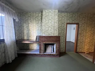 Sala de estar com lareira de tijolos e papel de parede de folhagem.