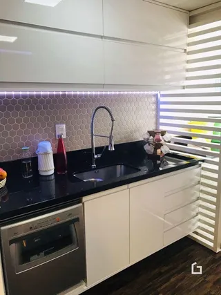 Uma cozinha moderna com armários brancos e bancadas escuras.