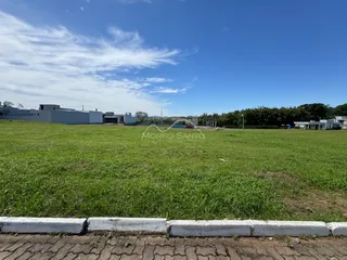 Vista aérea de um campo gramado aberto com estruturas ao fundo.