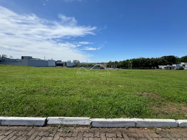 Vista aérea de um campo gramado aberto com estruturas ao fundo.