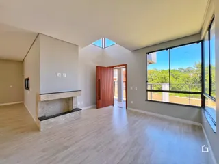 Sala de estar ampla com piso de madeira clara e lareira.