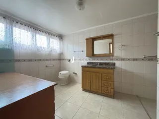 Foto de um banheiro com revestimento de azulejos brancos e piso claro.