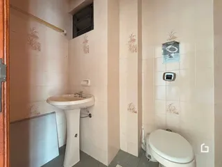 Foto interna de um banheiro com azulejos brancos e louças sanitárias.