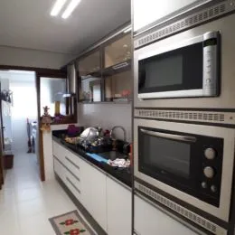 Uma cozinha com armários brancos e bancadas escuras é visível na propriedade.