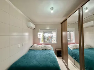 Quarto com cama azul turquesa e janela com vista externa.