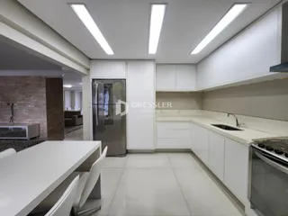 Uma cozinha moderna com armários brancos e eletrodomésticos de aço inoxidável é visível.