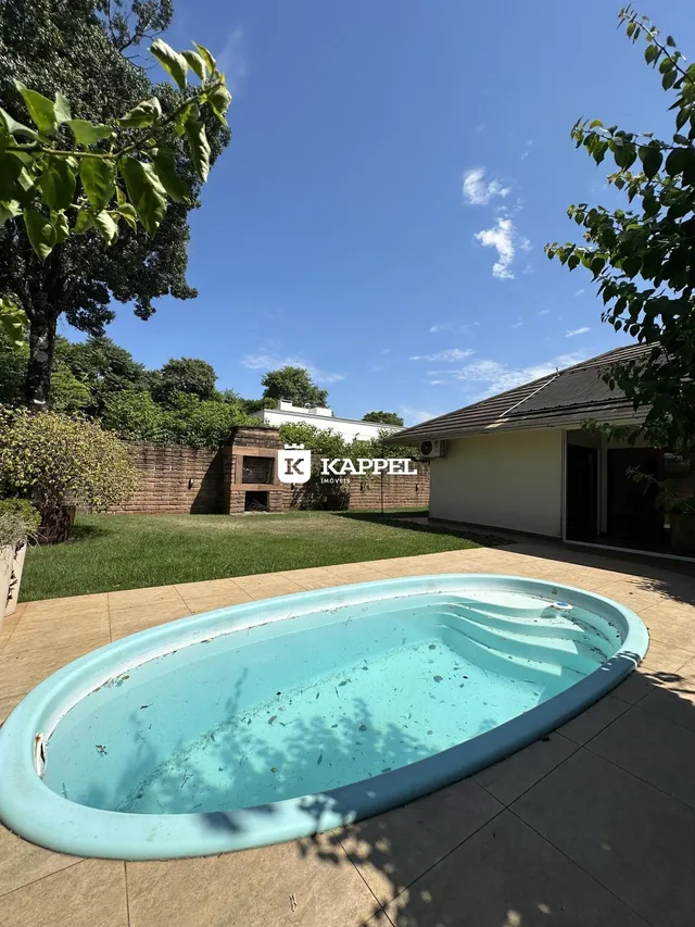Foto de uma piscina externa em um pátio com vegetação ao fundo.
