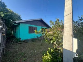 Fachada de uma casa azul-turquesa em Lajeado, Brasil, com vegetação ao redor.
