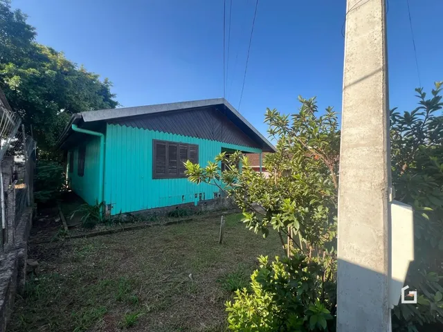 Fachada de uma casa azul-turquesa em Lajeado, Brasil, com vegetação ao redor.