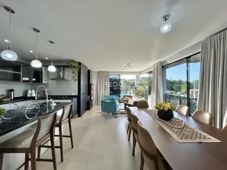 Ambiente moderno de sala de estar com cozinha integrada e mesa de jantar.