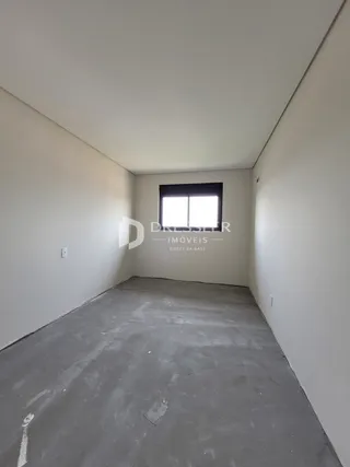 Espaço interno vazio com paredes brancas e piso de concreto.