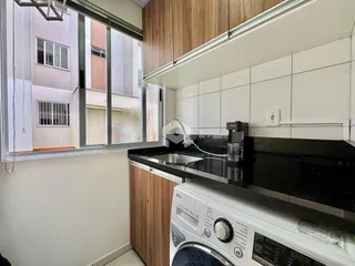 Vista da cozinha com armários de madeira e bancada escura.