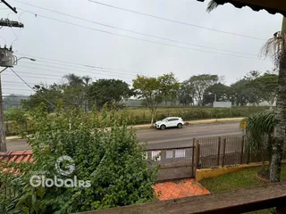 Vista externa de uma propriedade com cerca e vegetação ao lado de uma estrada.