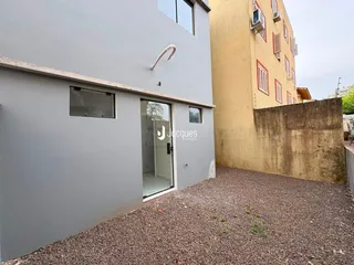 Fachada de uma residência em Lajeado, Brasil, com muro de contenção e piso de cascalho na frente.
