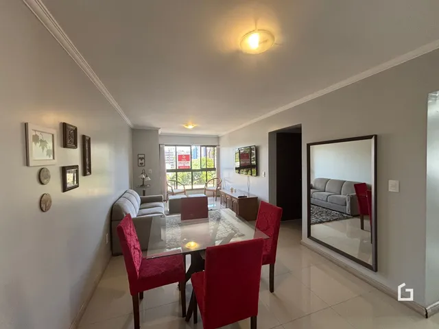 Sala de jantar com mesa de vidro e cadeiras vermelhas.