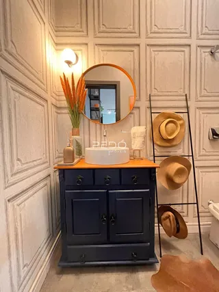 Quadro de uma cômoda azul escura com espelho em uma sala de estar.