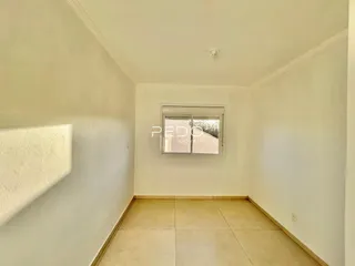 Corredor com piso de cerâmica e janela iluminada.