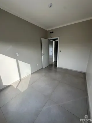 Hall de entrada com paredes brancas e piso de cerâmica.