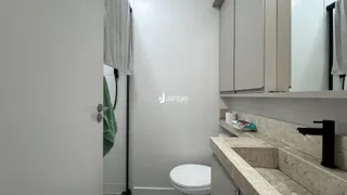 Vista parcial de um banheiro com azulejos brancos e bancada de granito.