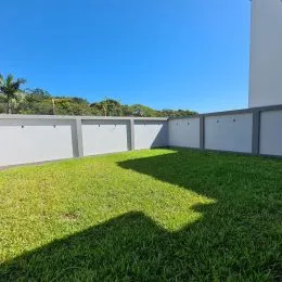 Vista de um gramado verde com cerca branca no exterior da propriedade.