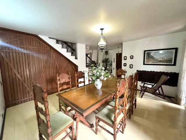 Uma sala de jantar com mesa de madeira e cadeiras de madeira.
