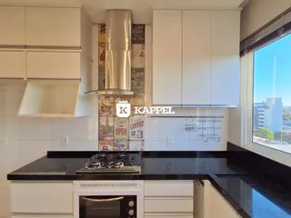 Cozinha moderna com armários brancos e bancadas escuras.