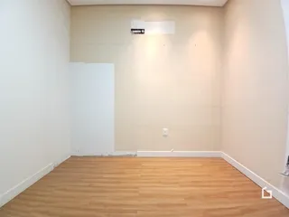 Foto de um cômodo interno com piso de madeira clara e paredes brancas.