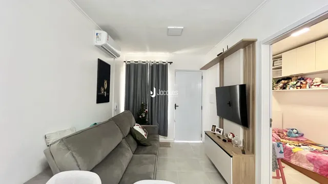 Sala de estar com sofá cinza e cortinas.