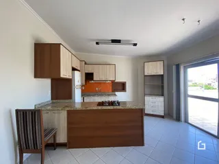 Sala de estar com cozinha integrada em um ambiente claro.