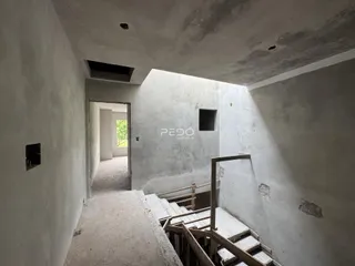 Vista de um corredor interno com paredes brancas e escadas de concreto.