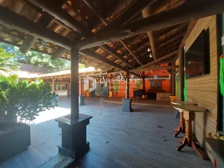 Área externa coberta com piso de madeira e vigas expostas.