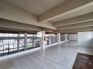 Hall de um imóvel com piso de cerâmica e estrutura de concreto aparente.