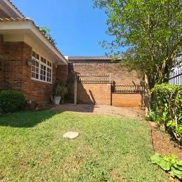 Fachada de casa de tijolos com gramado verde.