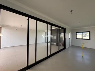 Ambiente interno de uma sala ampla com portas de vidro de caixilho preto.