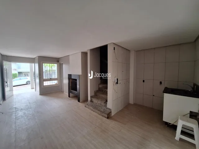 Ambiente interno de uma sala de estar com piso claro e paredes brancas.
