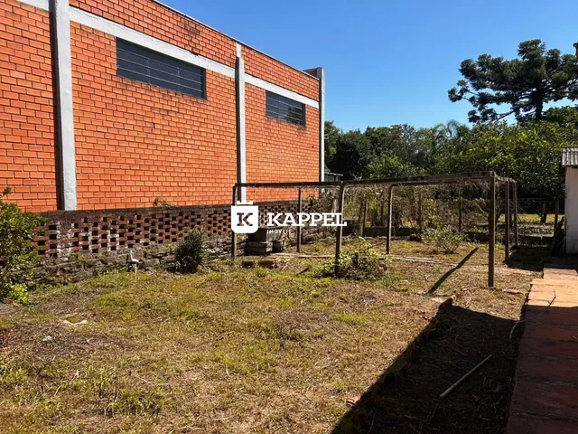 Fachada de um imóvel com alvenaria de tijolos e um terreno com vegetação rasteira.