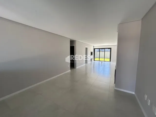 Corredor interno de uma residência com paredes brancas e piso claro.